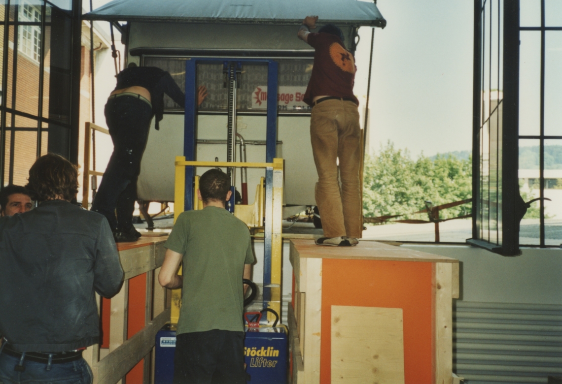 Der message salon Wohnwagen wird mit vereinten Kräften in den Ausstellungsraum gehievt. Foto Migros Museum Zürich