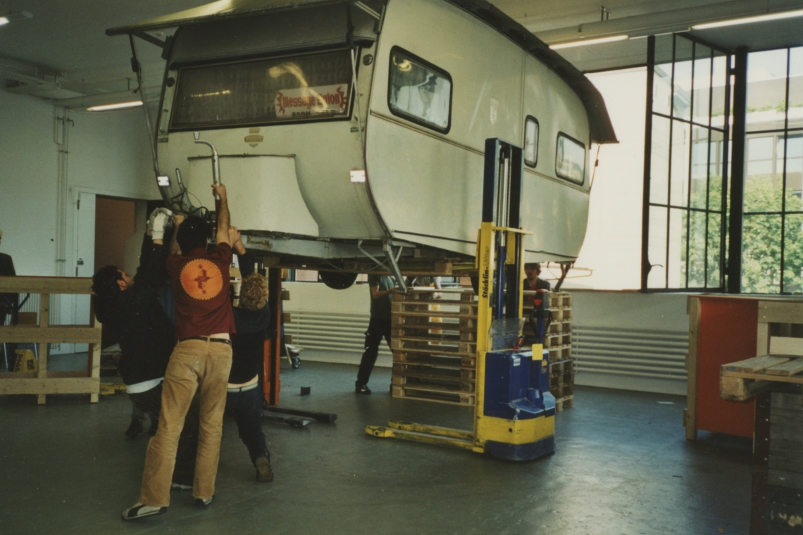 Der message salon Wohnwagen wird mit vereinten Kräften in den Ausstellungsraum gehievt. Foto Migros Museum Zürich